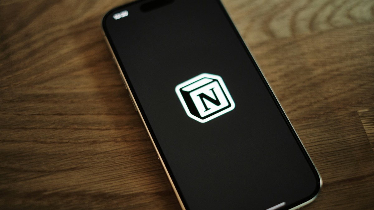 A phone showing the Notion logo on a wooden table